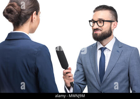 Lächelnd männlichen Journalisten interviewen Geschäftsfrau in Anzug, isoliert auf weißem Stockfoto