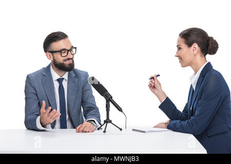 Lächelnd weibliche Journalist schriftlich in Notepad und interviewte Geschäftsmann, isoliert auf weißem Stockfoto