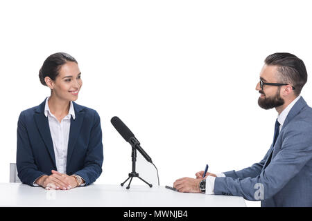 Lächelnd männlichen Journalisten interviewen Geschäftsfrau in Anzug, isoliert auf weißem Stockfoto