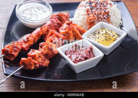 Chicken tandoori Spieße mit Reis und Saucen Stockfoto