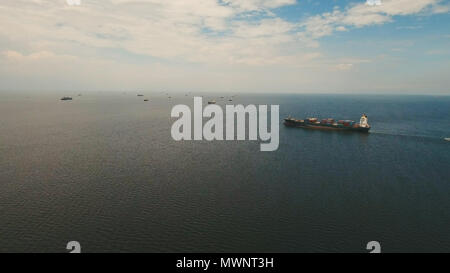 Luftaufnahme Frachtschiffe in der Bucht von Manila. Großen Containerschiff im Meer. Fliegen über die Wasseroberfläche im Meer mit Schiffen, blauen Himmel und Wolken. Philippinen, Manila. Stockfoto