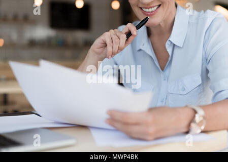 7/8 Schuß von lächelnden Geschäftsfrau arbeiten mit Papieren Stockfoto