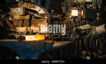 Schlosser schlägt das heiße Bügeleisen um die gewünschte Form zu geben. Stockfoto