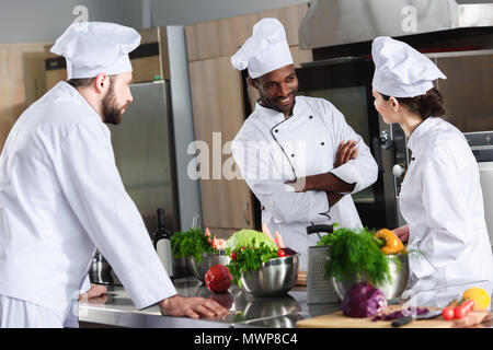 Multirassischen Köche Team diskutieren neue Rezeptur durch die Arbeitsplatte in der Küche Stockfoto