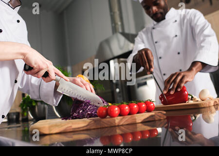 Multirassischen Köche team Schneiden von rohem Gemüse in der Küche Stockfoto