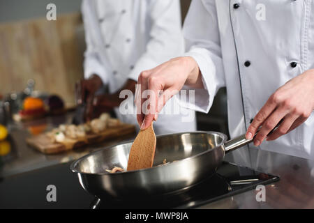 Nahaufnahme der Köchin das Kochen auf der Pfanne Stockfoto