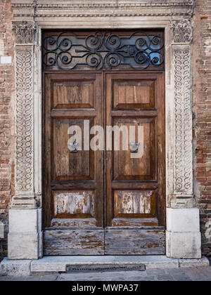 Alte hölzerne Portal mit Spalten und Architrav aus weißem Stein mit floralen Motiven geschnitzt. Stockfoto