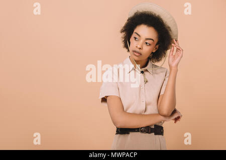 Stilvolle afrikanische amerikanische Frau in T-Shirt und Safari Hut isoliert auf beige Stockfoto