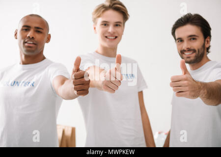 Gruppe von Happy multiethnischen Freiwilligen zeigen Daumen hoch Stockfoto