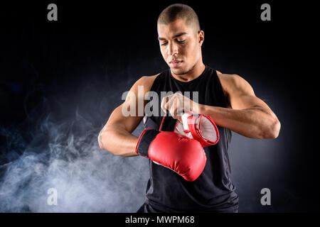 Junge afrikanische amerikanische Boxer auf Handschuhe auf Schwarz Stockfoto