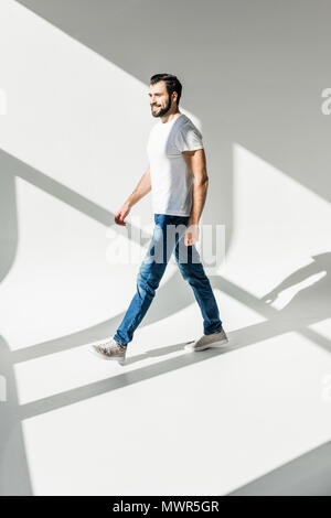Volle Länge von Stattlichen bärtiger Mann lächelnd und Wandern im Studio Stockfoto