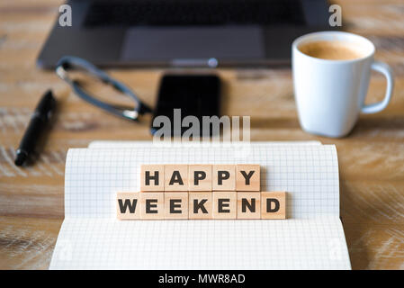Nahaufnahme auf das Notebook um Holz Tisch Hintergrund, auf Holzblöcken mit Buchstaben, Happy Weekend Text konzentrieren. Stockfoto