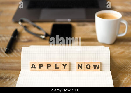 Nahaufnahme auf das Notebook um Holz Tisch Hintergrund, auf Holzblöcken mit Buchstaben machen Jetzt Bewerben Text konzentrieren. Stockfoto