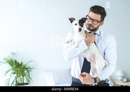 Gut aussehender Geschäftsmann in Brillen holding Jack Russell Terrier Hund Stockfoto
