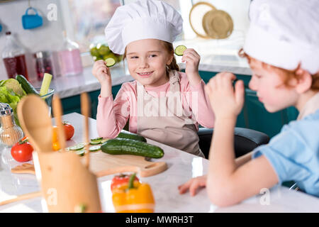 Süße kleine Kinder in kochmützen Spaß beim gemeinsames Kochen in der Küche Stockfoto