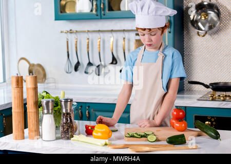 Cute little boy in Chef hat und Schürze Kochen in der Küche Stockfoto