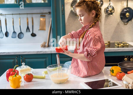 Adorable kleine Kind kochen beim Sitzen am Küchentisch Stockfoto