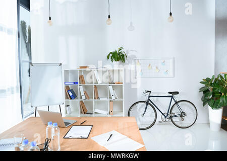 Blick auf leeren Büro Interieur mit Tisch und Fahrrad gegen die Wand Stockfoto