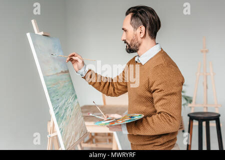 Seitenansicht des bärtigen Mann malen auf Gestell an Kunst Klasse Stockfoto