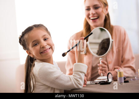 Schöne glückliche Mutter und Tochter Make-up zusammen zu Hause anwenden Stockfoto