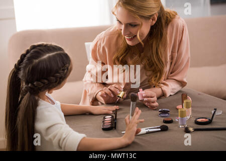 Glückliche Mutter und Tochter Anwendung Make-up zusammen zu Hause Stockfoto