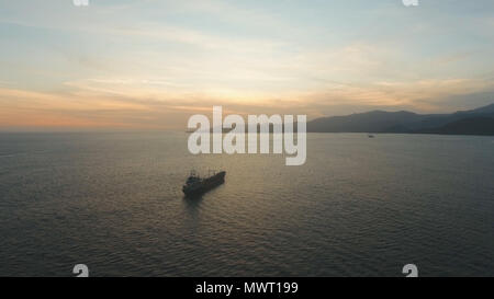 Luftaufnahme Frachtschiff im Meer bei Sonnenuntergang. Sonnenuntergang über dem Meer. Fliegen über den blauen Ozean mit blauen Wasser, Himmel. Bali, Indonesien. Travel Concept. Stockfoto