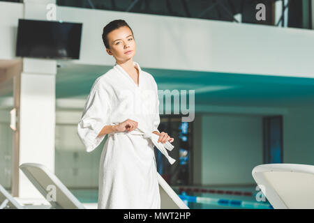 Schöne junge Frau binden Gürtel von Bademantel im Spa Stockfoto