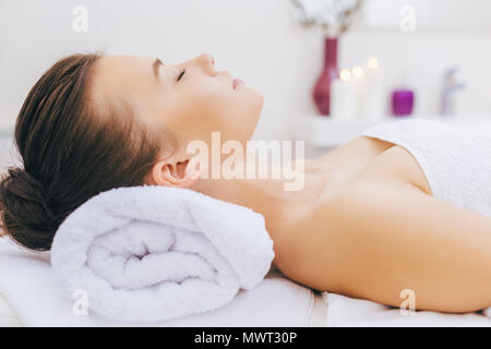Schöne junge Frau Entspannen im Spa mit Kopf auf gerollt Handtuch Stockfoto