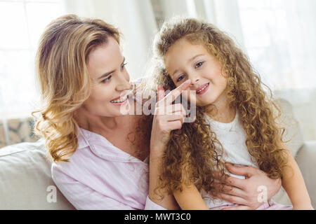 Glückliche Mutter Berühren der Nase Ihres curly Tochter Stockfoto