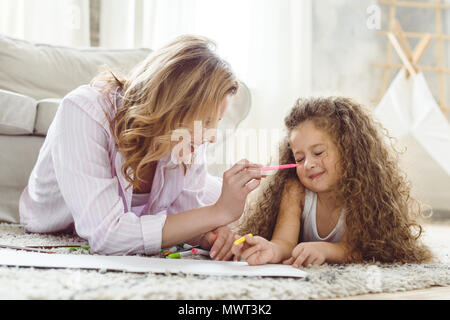 Curly Tochter und glückliche Mutter Zeichnung mit Markern und Spaß haben Stockfoto