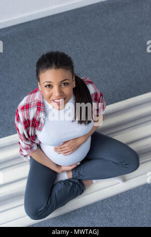 Ansicht von oben der lächelnden african american Schwangere Yoga auf der Matte Stockfoto