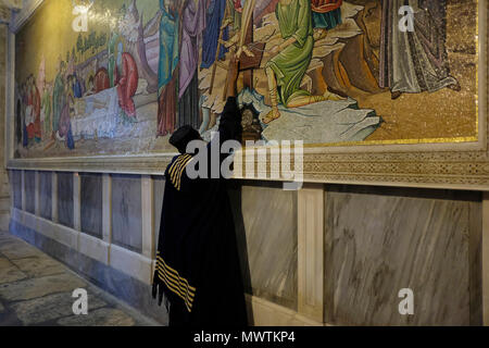 Ein christlich-äthiopisch-orthodoxer Pilger betet vor einem Wandmosaik, das den Körper Jesu Christi darstellt, der nach seinem Tod vorbereitet wird, gegenüber dem Stein von Anointing.inside die Grabeskirche in der Altstadt des Christlichen Viertels Ostjerusalem Israel Stockfoto