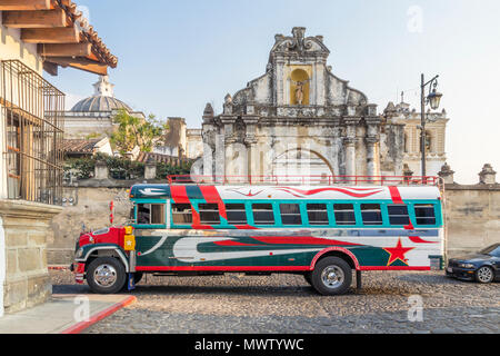 Eine typische bunt bemalten Chicken Bus vorbei am Eingang der Kirche San Francisco in Antigua, UNESCO, Guatemala, Mittelamerika Stockfoto