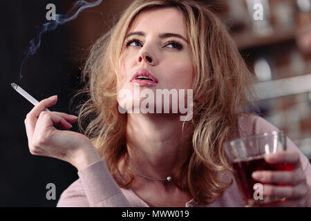 Portrait von nachdenklich Frau mit Glas Alkohol und Zigaretten Stockfoto