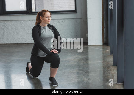 Übergewichtige Mädchen Durchführung Dehnungsübungen in der Turnhalle Stockfoto