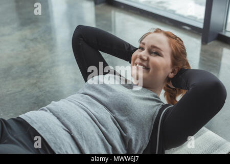 Übergewichtige Mädchen durchführen Sit Ups in der Turnhalle Stockfoto