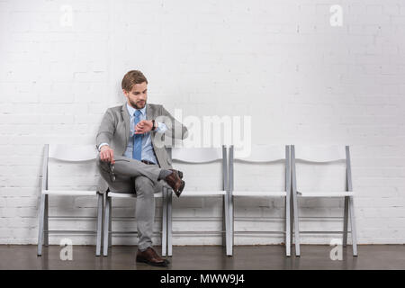 Kaukasische Geschäftsmann Kontrolle Zeit beim Warten auf Job Interview Stockfoto