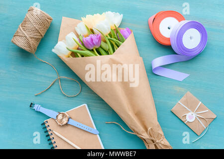 Blick von oben auf die schöne Tulpen im Handwerk Papier, Seile, Bänder, Umschlag und Notebook mit Armbanduhr Stockfoto