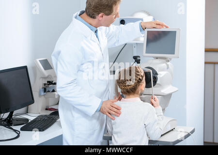 Rückansicht der Augenarzt untersuchen Vision von jugendlicher Kind in Klinik Stockfoto