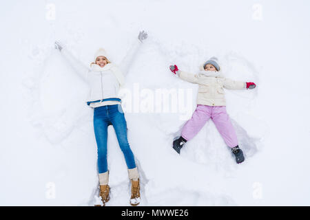 Blick von oben auf die glückliche Mutter und Tochter machen Schnee Engel zusammen Stockfoto