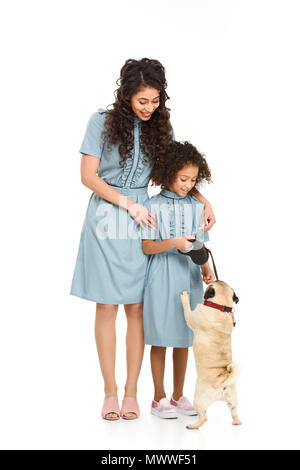 Mutter und Tochter spielen mit Mops Welpen isoliert auf weißem Stockfoto