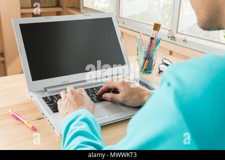 Grüne t-shirt Geschäftsmann eingabe Laptop oder Notebook im Home Office. Kleine und mittlere Unternehmen KMU oder starten Sie Geschäftsmann Konzept. Wirtschaft und Technologie Stockfoto