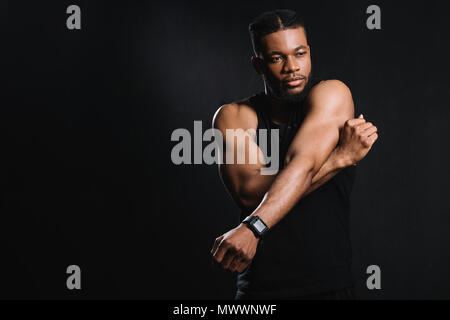 Muskulöse afrikanische amerikanische Mann stretching Hände isoliert auf Schwarz Stockfoto