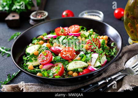 Salat von Kichererbsen, Tomaten, Gurken, Rettich und Grüns. Diätetische Lebensmittel. Vegan Salat. Stockfoto