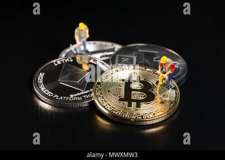 Miniatur Arbeiter Bergbau verschiedene Cryptocurrencies auf eine schwarze Fläche Stockfoto