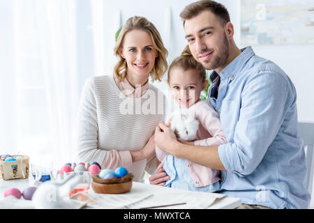 Happy Family Holding Osterhase mit Ostereiern auf Tisch Stockfoto