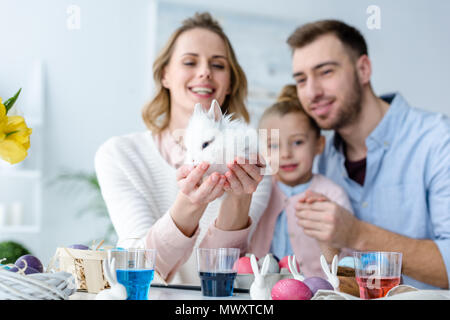 Mutter mit der Familie Holding cute Bunny von Tabelle mit Ostereiern Stockfoto