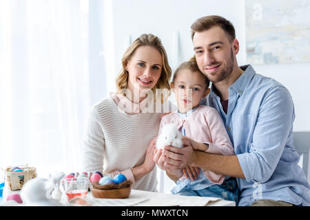 Happy Family Holding Ostern Hase mit bemalte Eier auf Tisch Stockfoto