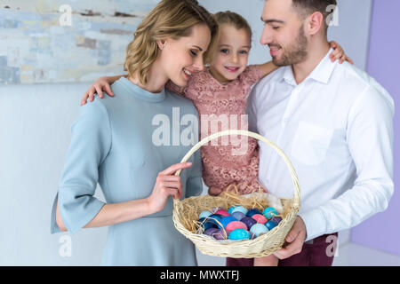 Lächelnd Familie holding Korb mit bemalten Ostereier Stockfoto