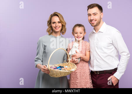 Eltern und Tochter holding Korb mit Ostereiern isoliert auf Violett Stockfoto